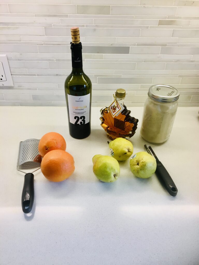 pears, wine, sugar, honey, orange, potato peeler, zest peeler on countertop.