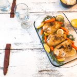 baked chicken with rosemary, lemon and carrot on a wooden table