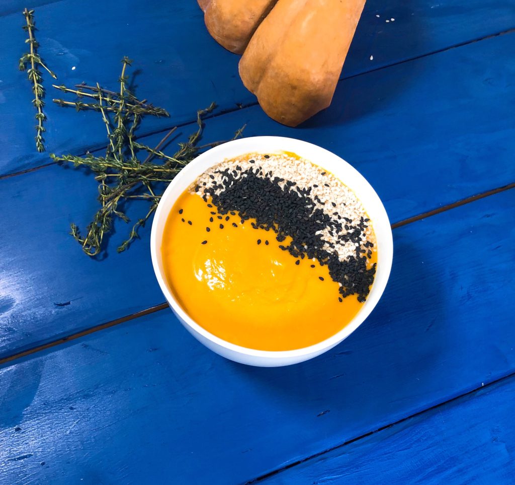 un bol de soupe au potiron sur une table en bois bleu