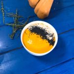 a bowl of pumpkin soup on a blue wooden table