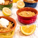 small pots of apple crumble with sliced lemons on marble top
