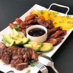 beef, plantains, mangoes, avocados on white platter