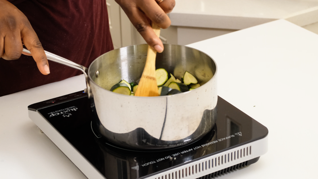 stirring zucchini in a pot on the stove