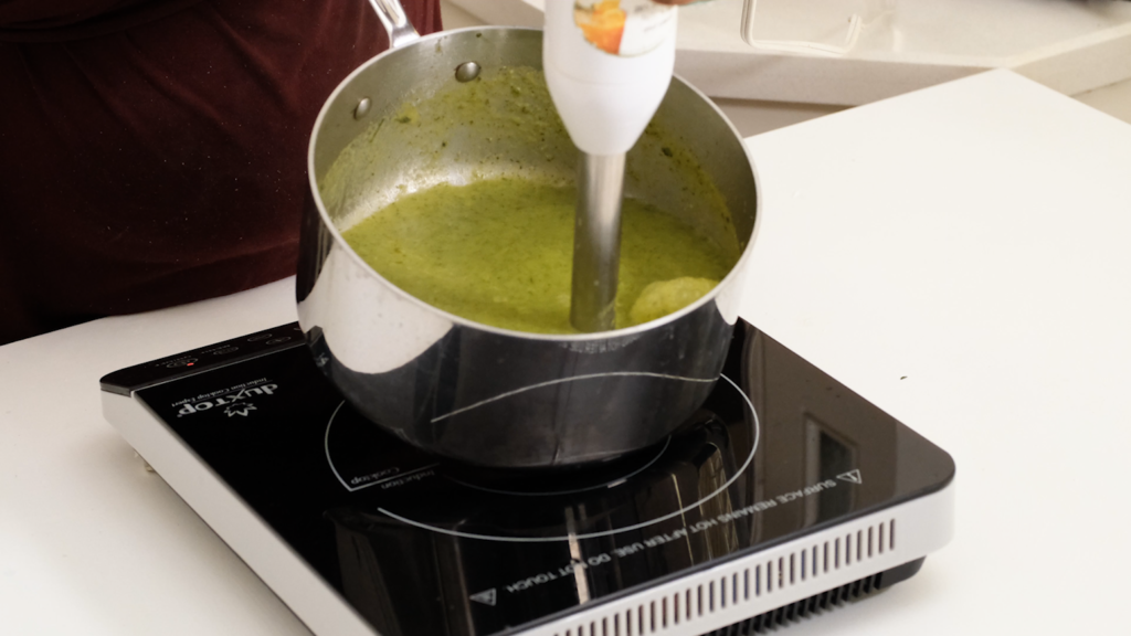 mixing zucchini soup in the pot with hand mixer