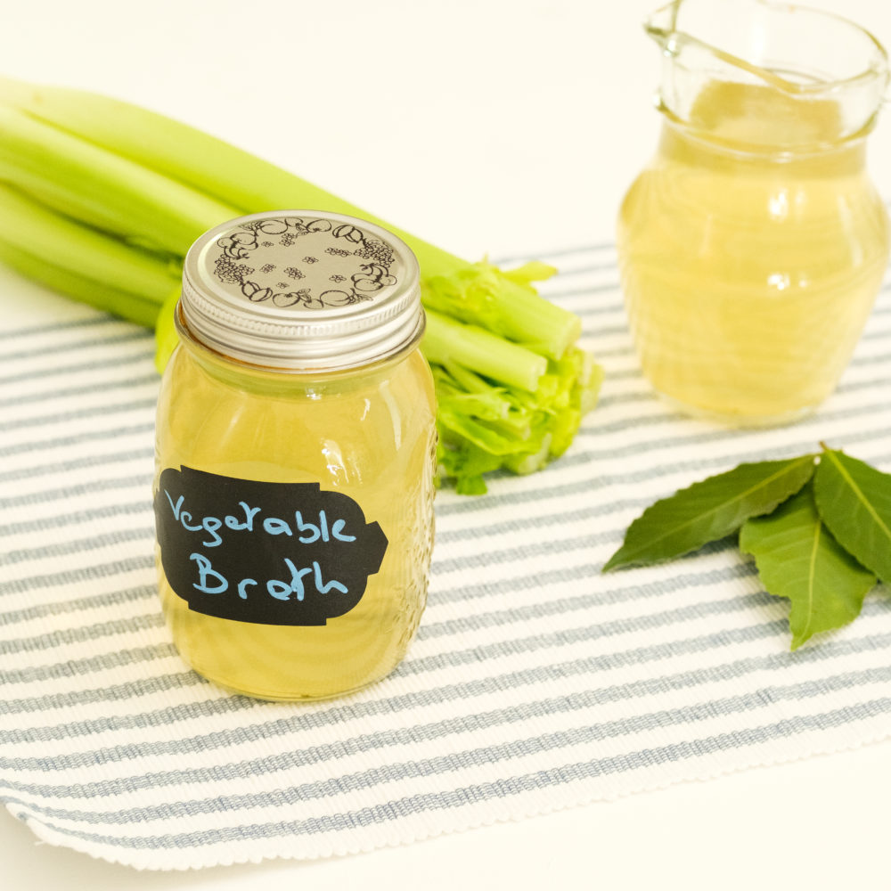vegetable broth in a jar with celery stalks next to it