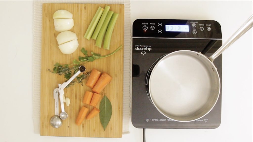 a cutting board with vegetables on it and a pot on the stove next to it.
