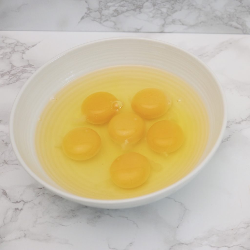 cracked eggs in white bowl