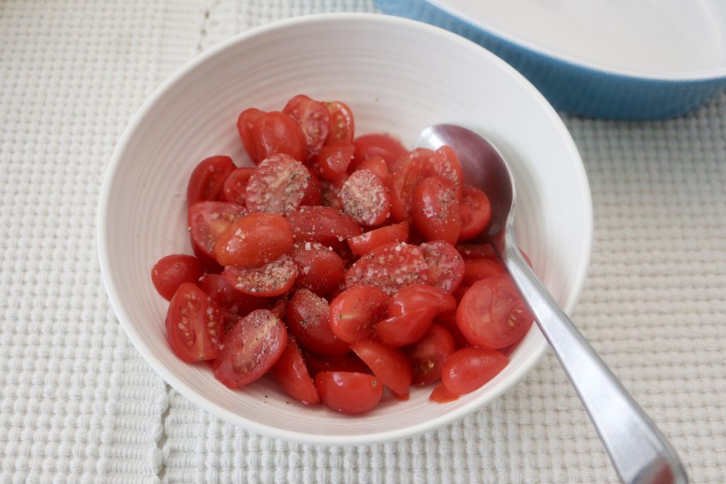 tomatoes halves in a bowl with salt and pepper