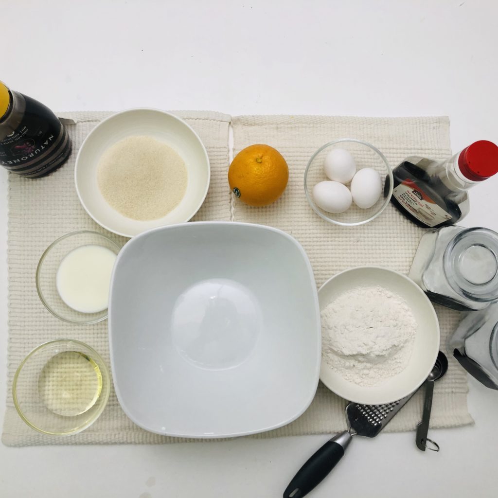 eggs, flour, orange, vanilla, oil, sugar, honey, milk, salt on a table