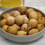 Beignets africains (puff puff) dans un bol gris avec sauce à la mangue à part