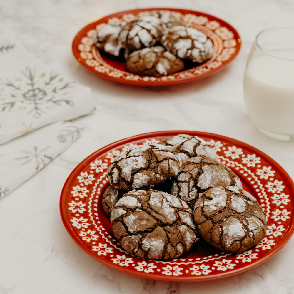 chocolate crinkles on red plate with a glass of milk to the side