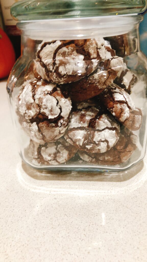 Stack of soft chocolate crinkle cookies with powdered sugar cracks and bright orange zest for holiday dessert in a jar
