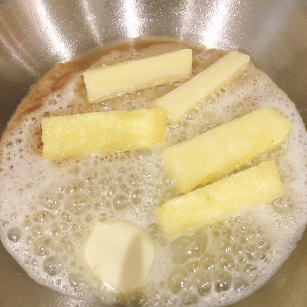 pineapple being fried in a pan with butter