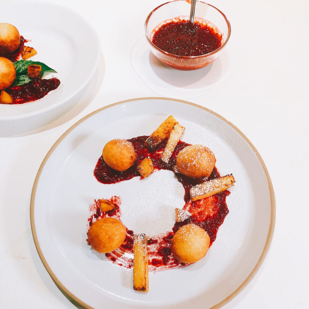African beignets with raspberry sauce in white plate