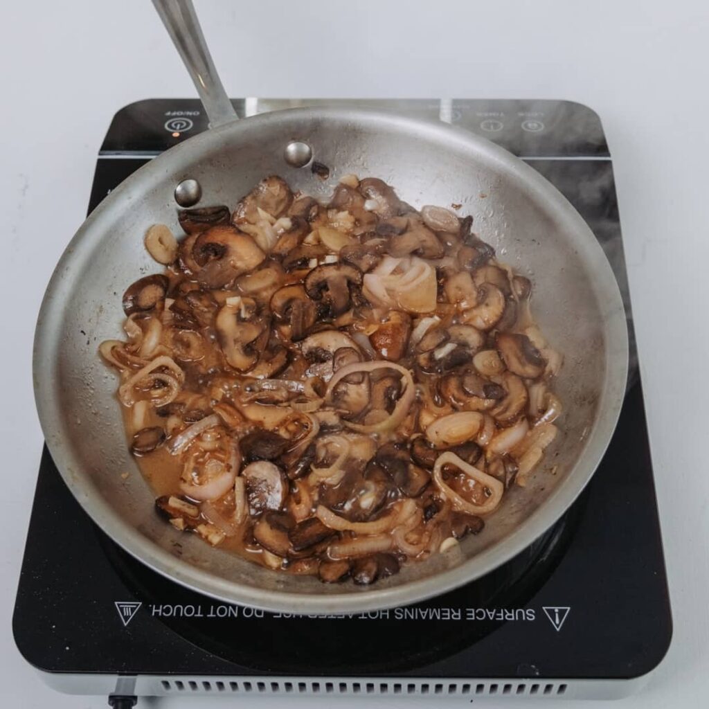 mushrooms being cooked in sauce pan