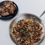 mushrooms in sauce pan with lamb ribeye on plate
