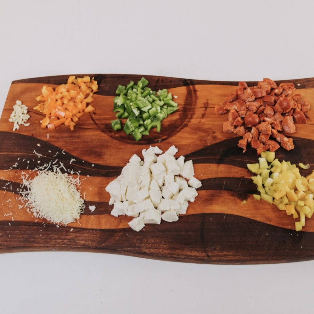 peppers, mozzarella, shredded cheese, chorizo on cutting board.