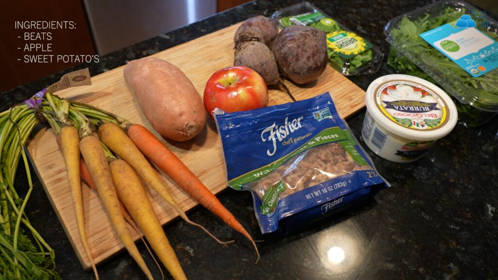 carrots, beets, walnuts, apples, sweet potato,basi, arugula on a cutting board

