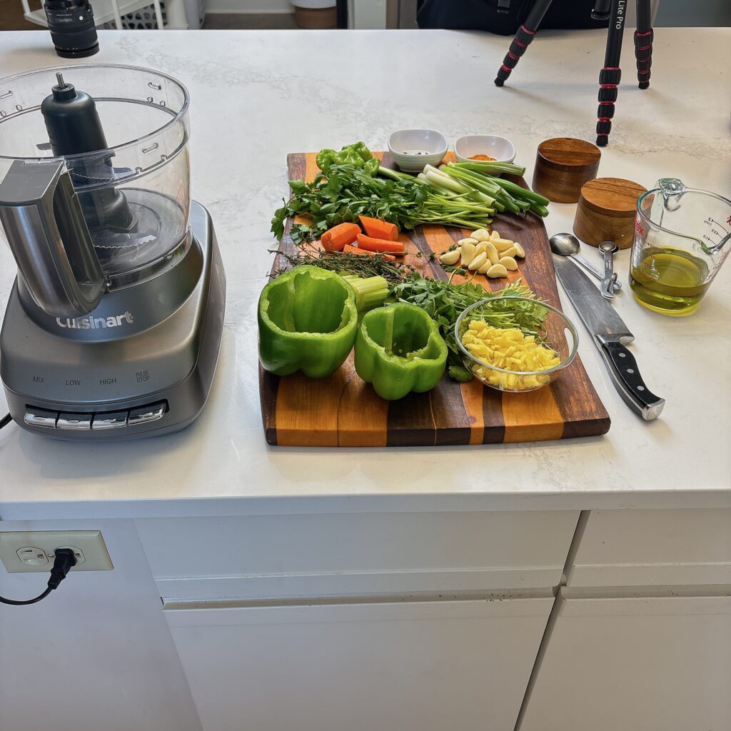 green pepper, ginger, green onions, carrots, garlic on a cutting board next the mixer