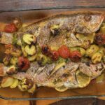 roasted red snapper with potatoes and epis seasoning in a clear baking plate