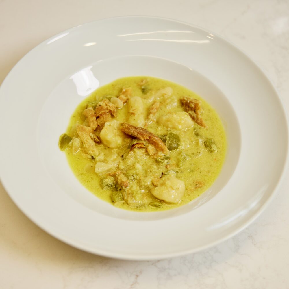 Cassava gnocchi with egusi and smoked fish served on a white plate