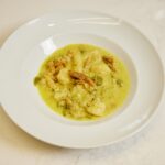 Gnocchi de manioc à l'egusi et au poisson fumé servis sur une assiette blanche