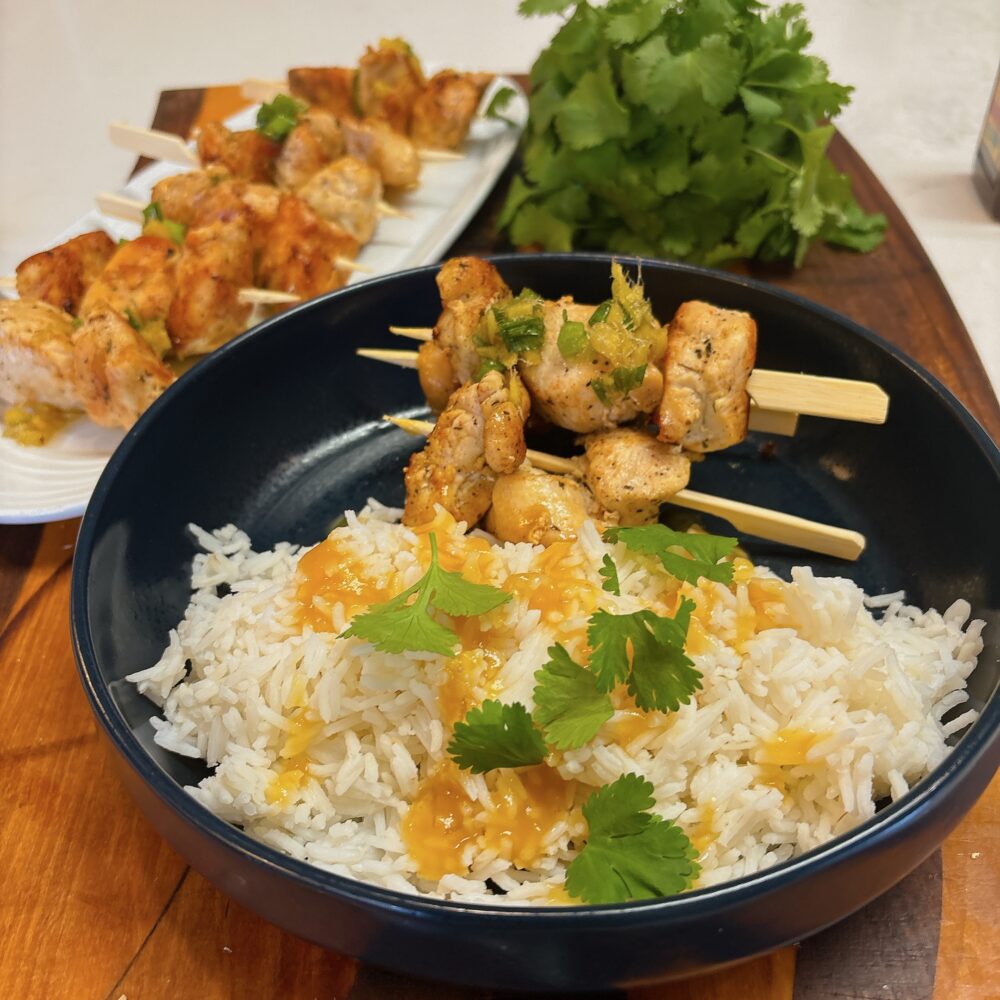 a bowl of white rice with chicken kebabs and mango sauce