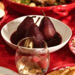 poached pears in red wine in beige bowl on red table
