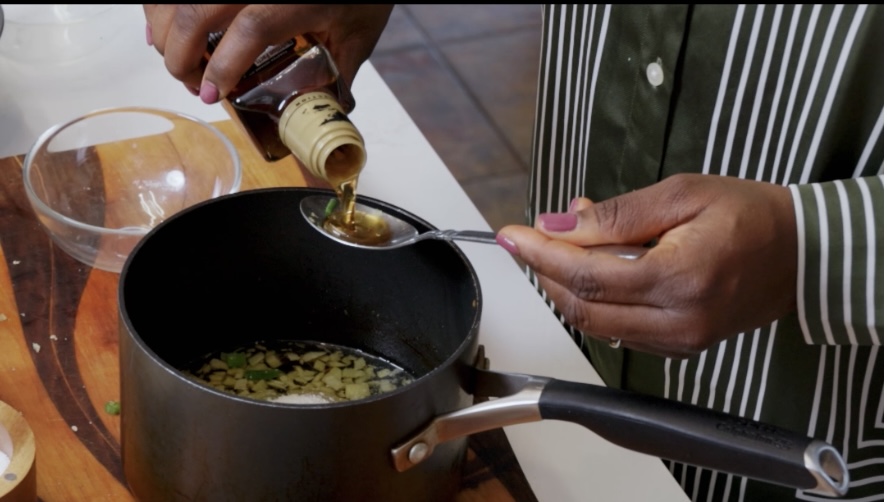 ginger and scallin sauce in a pot with sesame oil being poured