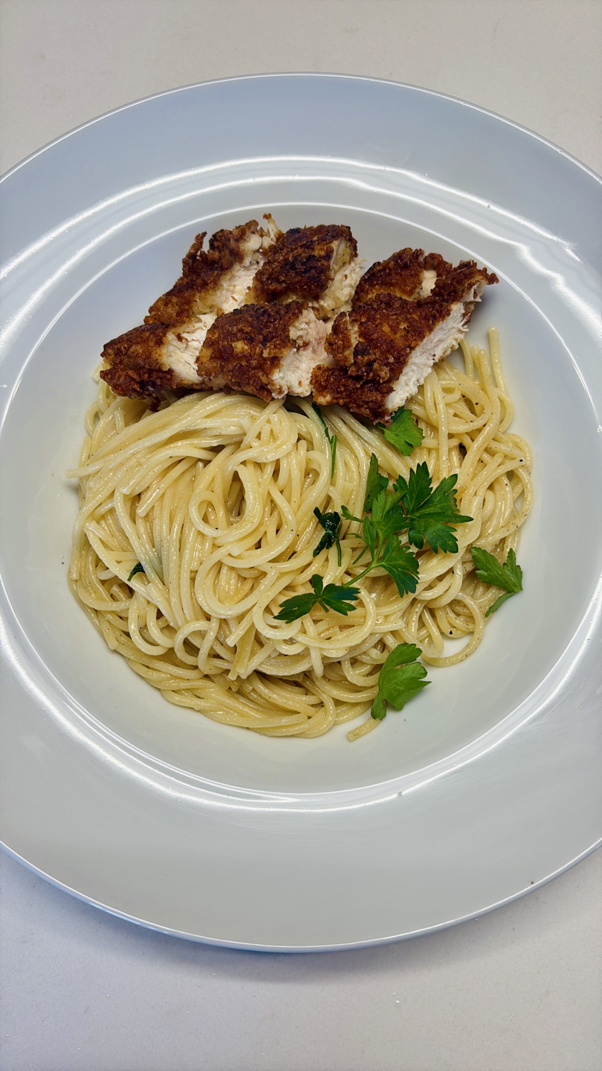 spaghetti with chicken parmesan on a white plate