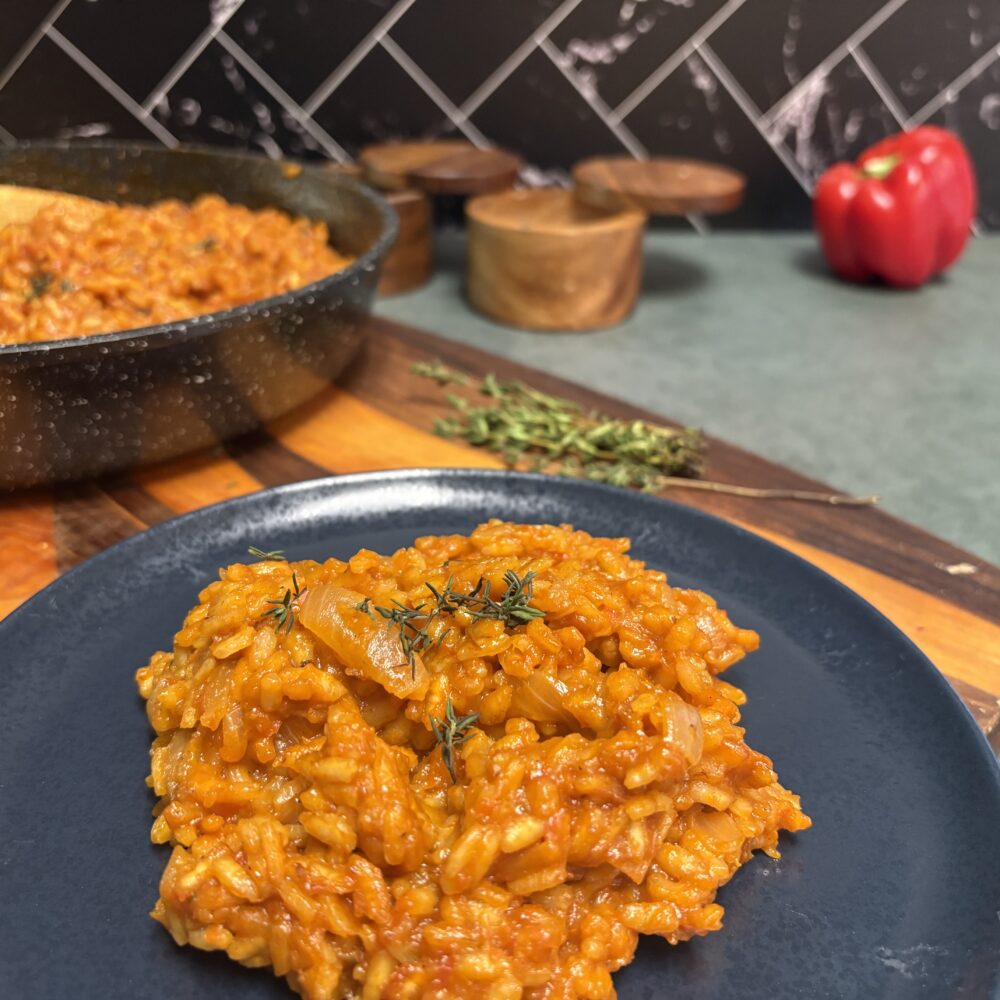 risotto crémeux au jollof sur une assiette bleue.