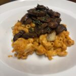 peanut butter mac n cheese with mushroom in white pasta plate