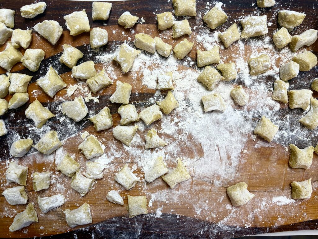 plantain gnocchi on a wooden cutting board with flour spread on them