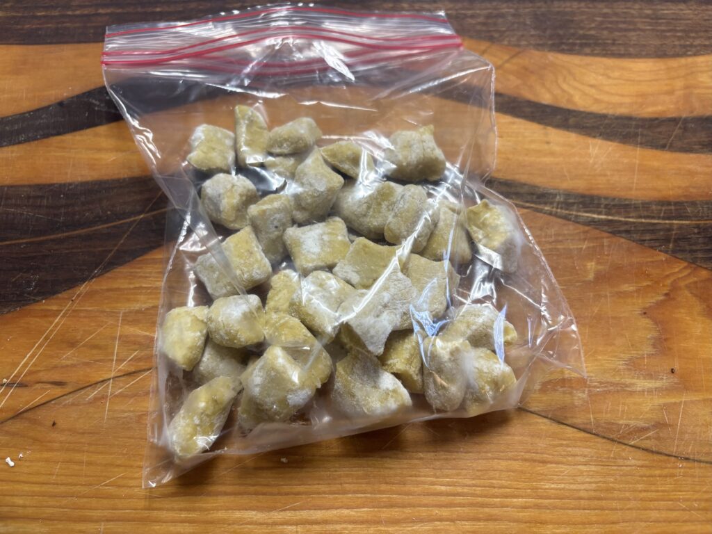 uncooked gnocchi in a plastic bag placed on a cutting board.