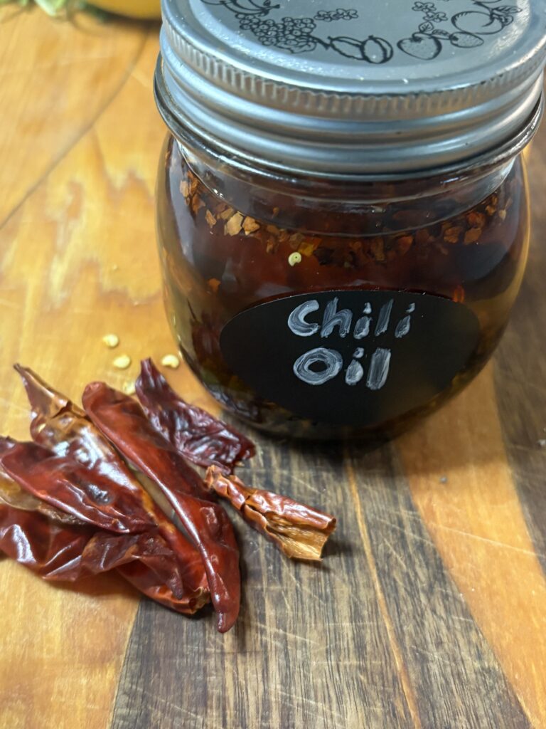 de l'huile pimentée dans un petit bocal en verre, avec du piment séché à côté.