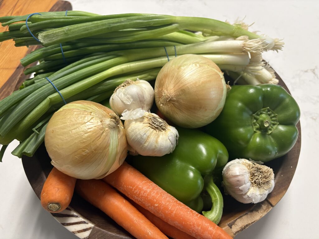poivrons, oignons, oignons verts, carottes et ail dans un saladier en bois.